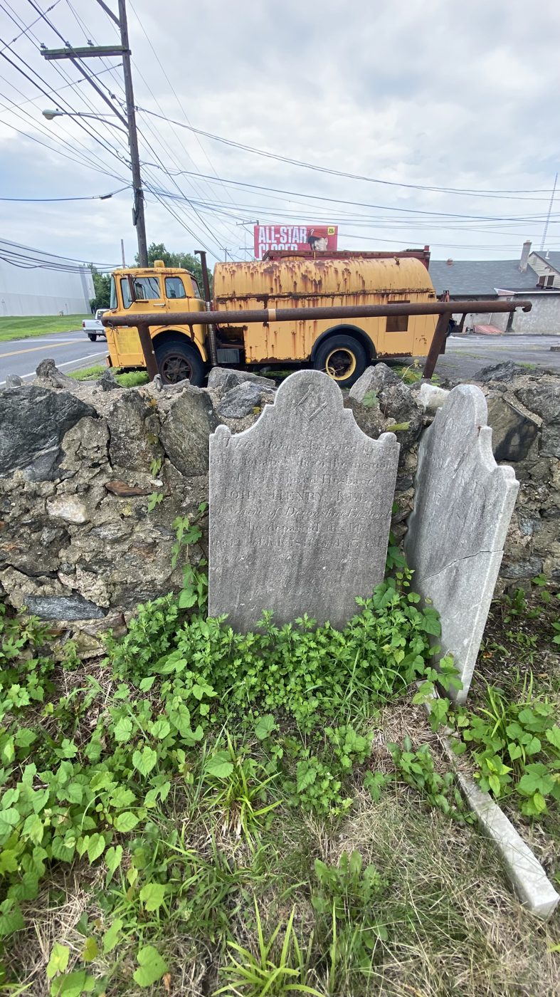 Close view of leaning headstones by the wall